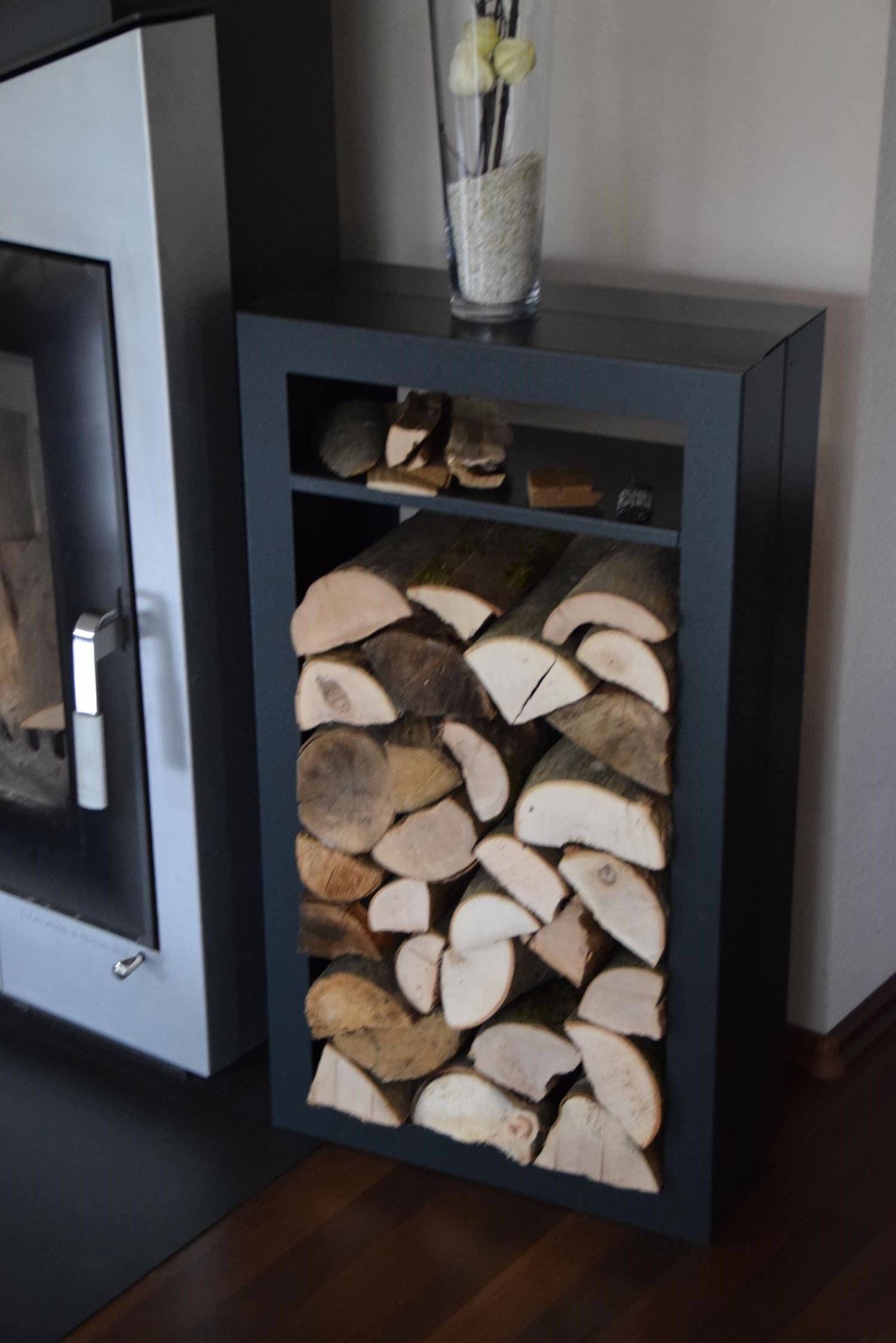 Holzregal aus Metall in Anthrazit mit Fach, steht neben einem Kamin