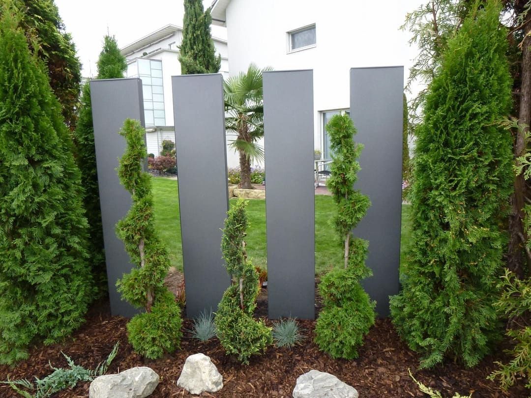 graue Metall Gartenstelen als Sichtschutz zwischen Hecken