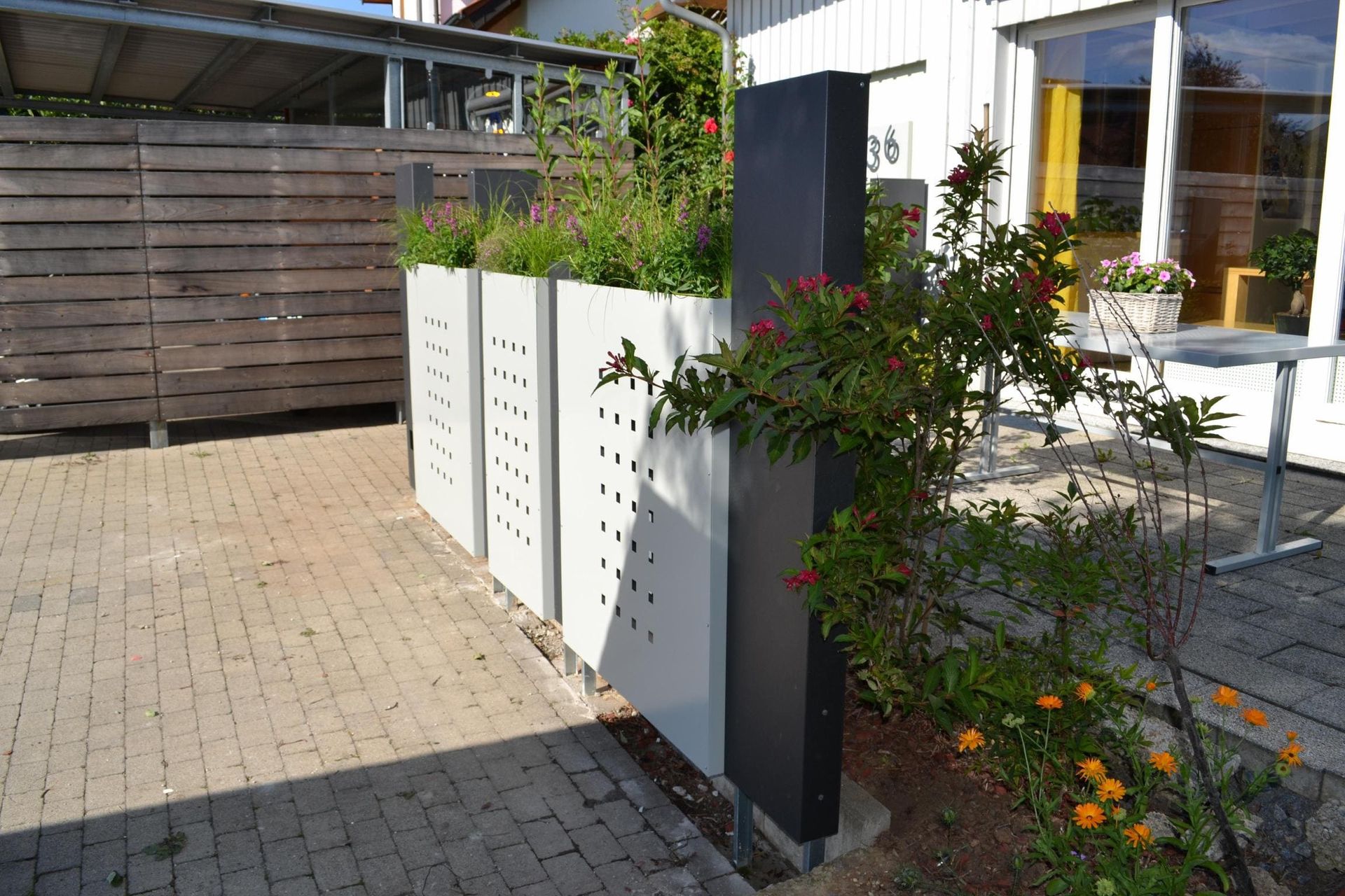 Begrünte Pflanzkübel aus Metall als Zaunsystem vor einer Terrasse