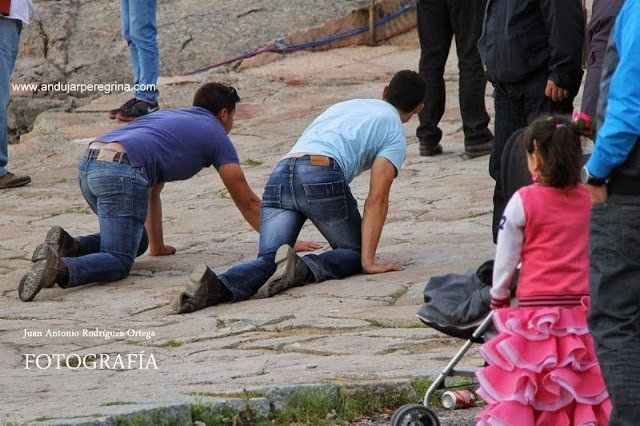 dos peregrinos subiendo la calzada de rodillas en promesa