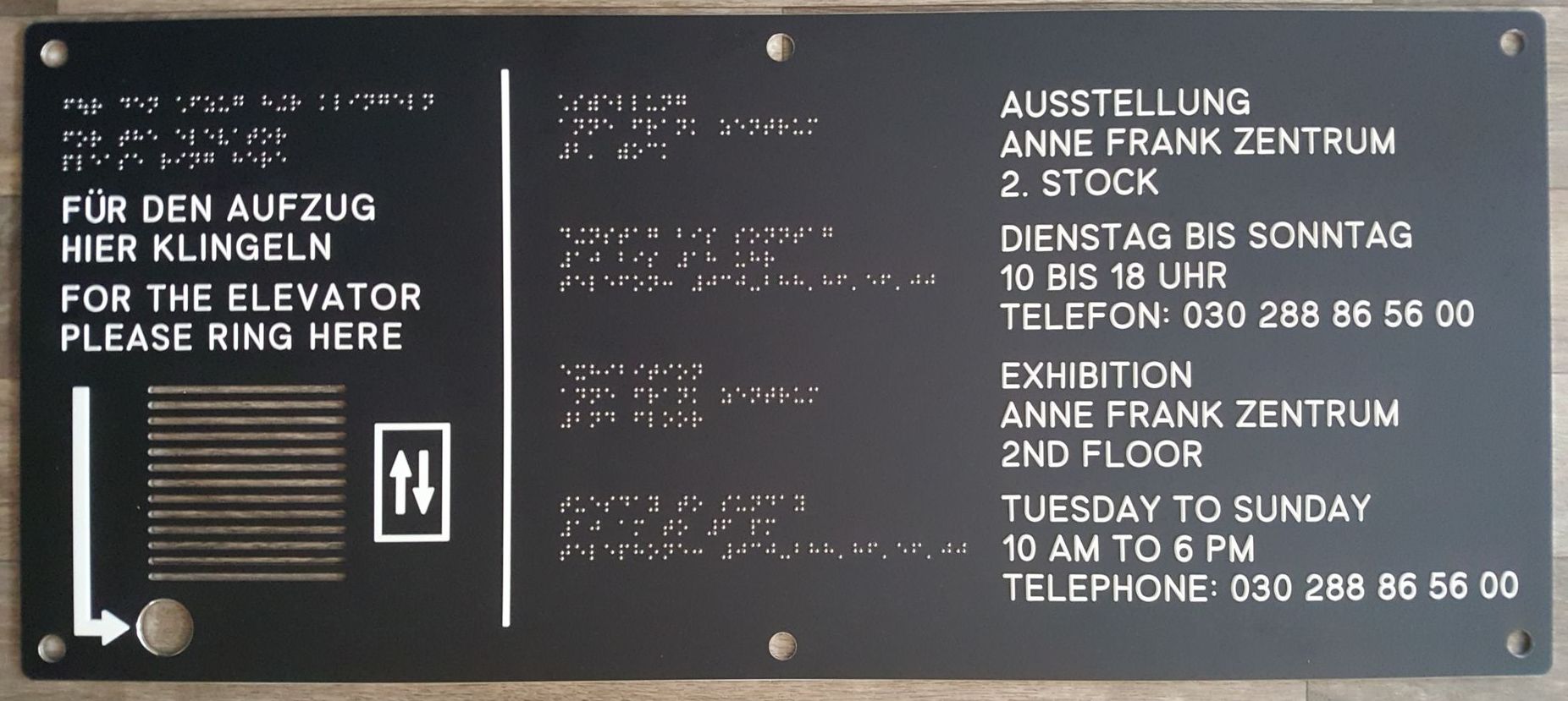 unser mehrsprachiges Wandschild, das speziell für das Anne Frank Zentrum entworfen wurde. Es bietet wichtige Informationen über die anstehende Ausstellung, einschließlich Datum, Uhrzeit und Ort. Das Schild ist in deutscher und englischer Sprache sowie in Braille verfügbar, um Barrierefreiheit zu gewährleisten. Es enthält auch Kontaktdaten für weitere Informationen und Anfragen. Dieses Wandschild ist ein hervorragendes Beispiel für inklusives Design, das Besucher aller Fähigkeiten einbezieht und informiert.