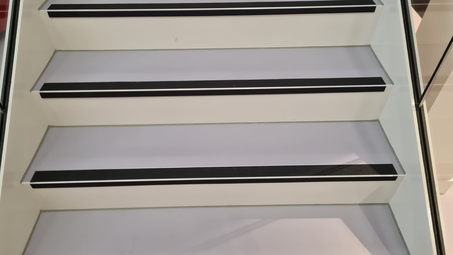 Vier weiße Treppenstufen mit schwarzen Treppenmarkierungen