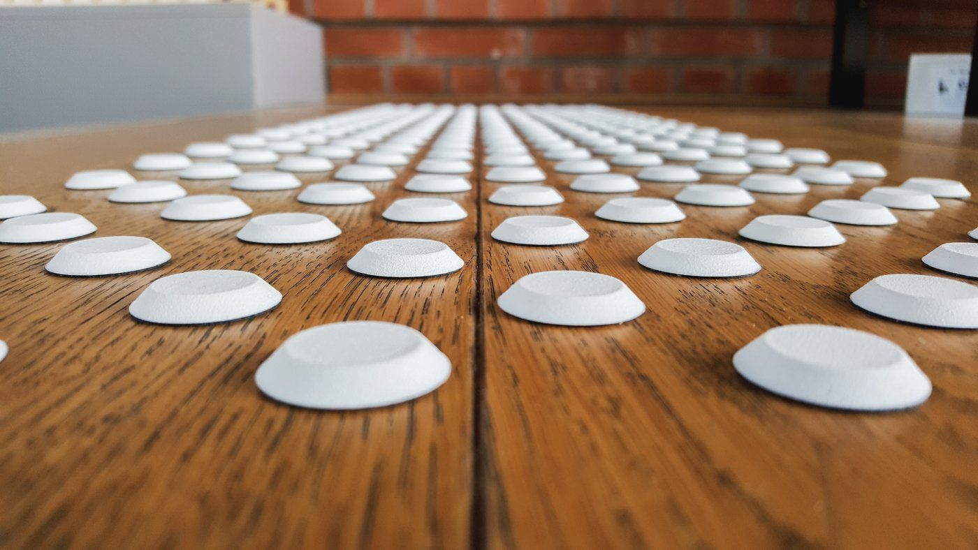 Weiße Noppen eines Bodenleitsystems aus Kunststoff auf Holzboden