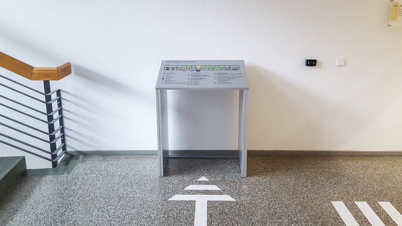 Ein taktiler Lageplan neben einer Treppe. Der Plan ist über ein Bodenleitsystem erreichbar.