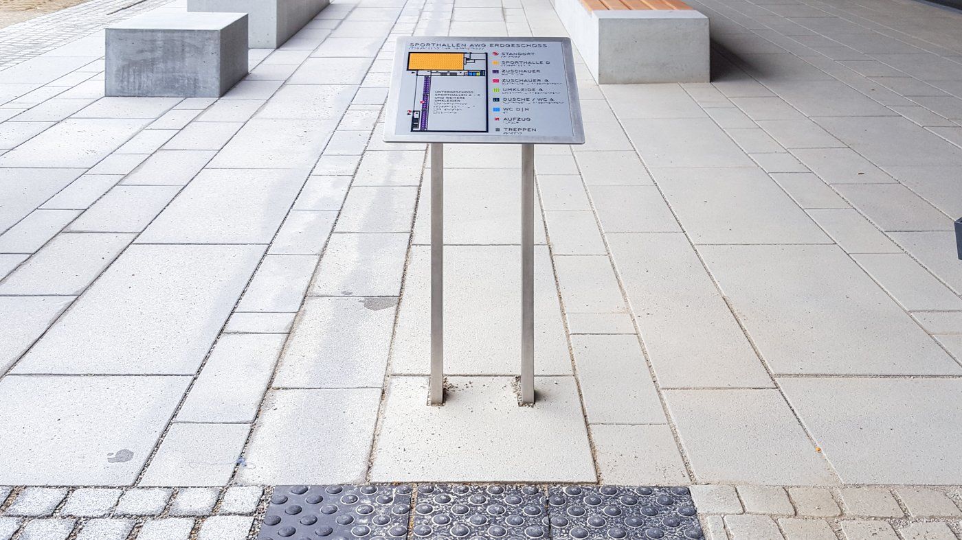 Ein taktiler Lageplan einer Sporthalle. Es sind die Zuschauerränge, WCs, Duschen, Aufzüge, Umkleiden und Treppen markiert.