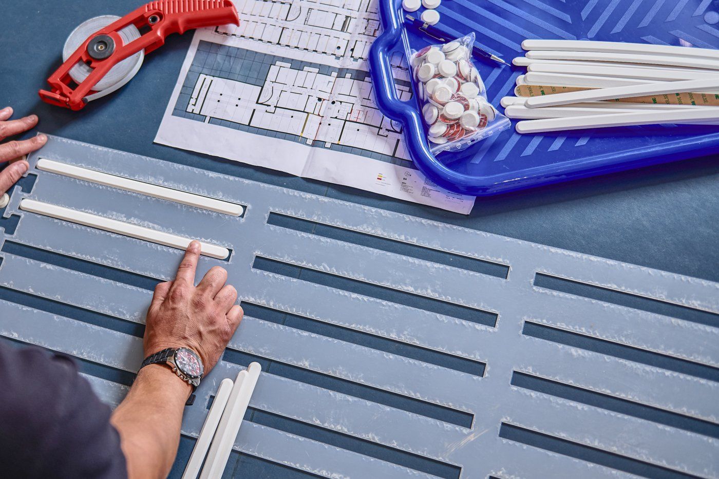 Ein Mitarbeiter der BARRIEREFREIHEIT GmbH verlegt, verklebt und montiert professionell Leitlinien mit Hilfe einer Schablone.