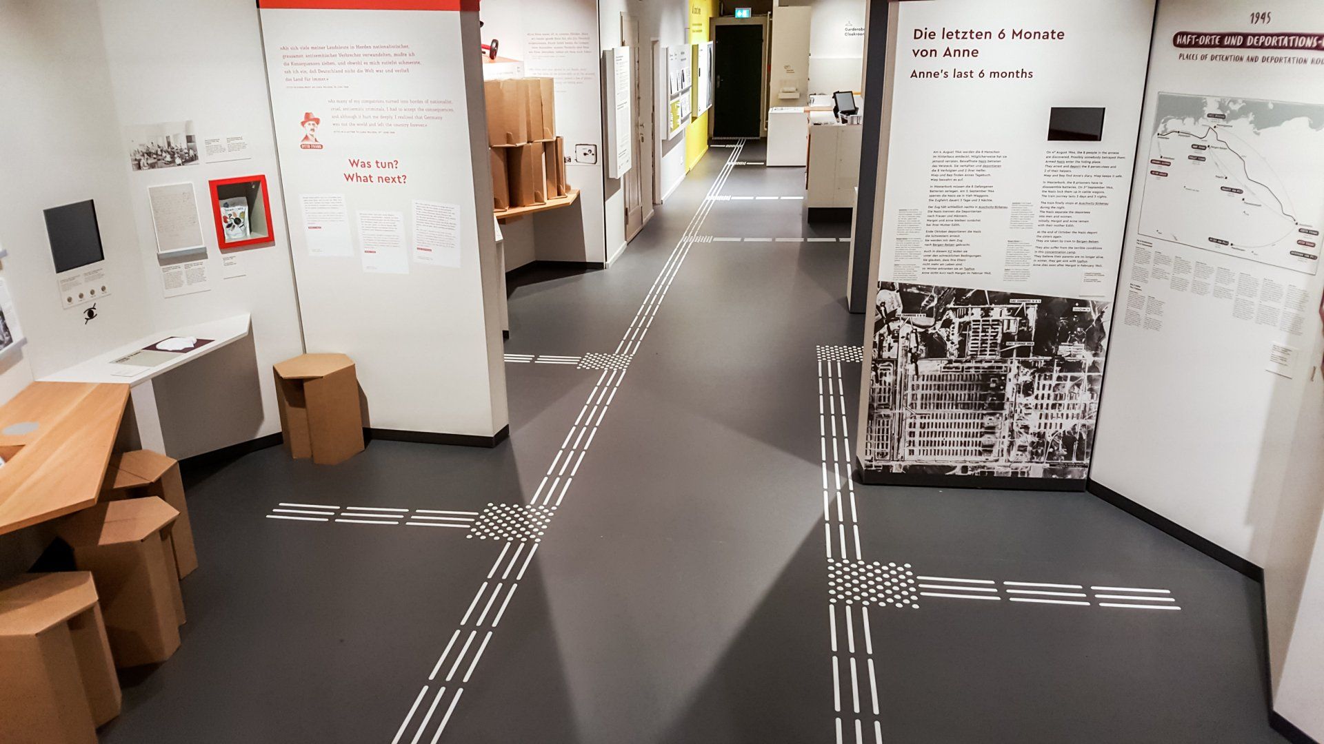 Ein Bodenleitsystem, welches durch einen Raum voller Informationstafeln führt.  Jede Informationstafel kann über das Leitsystem angelaufen werden.