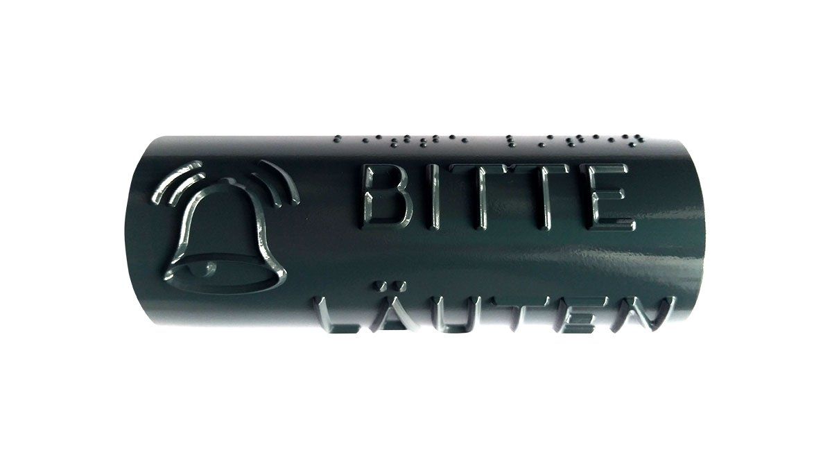 Ein taktiles Handlaufschild mit einer Glocke auf dem steht Bitte Läuten. Dunkelgraue Handlaufschilder aus. Die lateinischen Buchstaben sind oberhalb in Brailleschrift übersetzt.