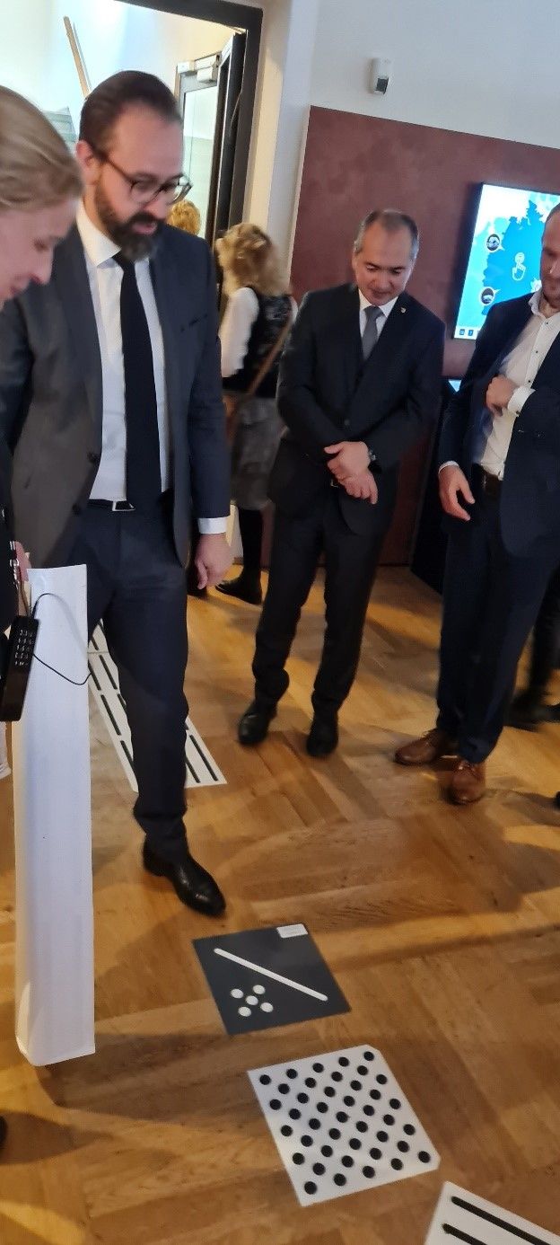 Mehrere Menschen stehen um einzelne Komponenten eines Bodenleitsystems herum. Sie tragen Anzüge.
