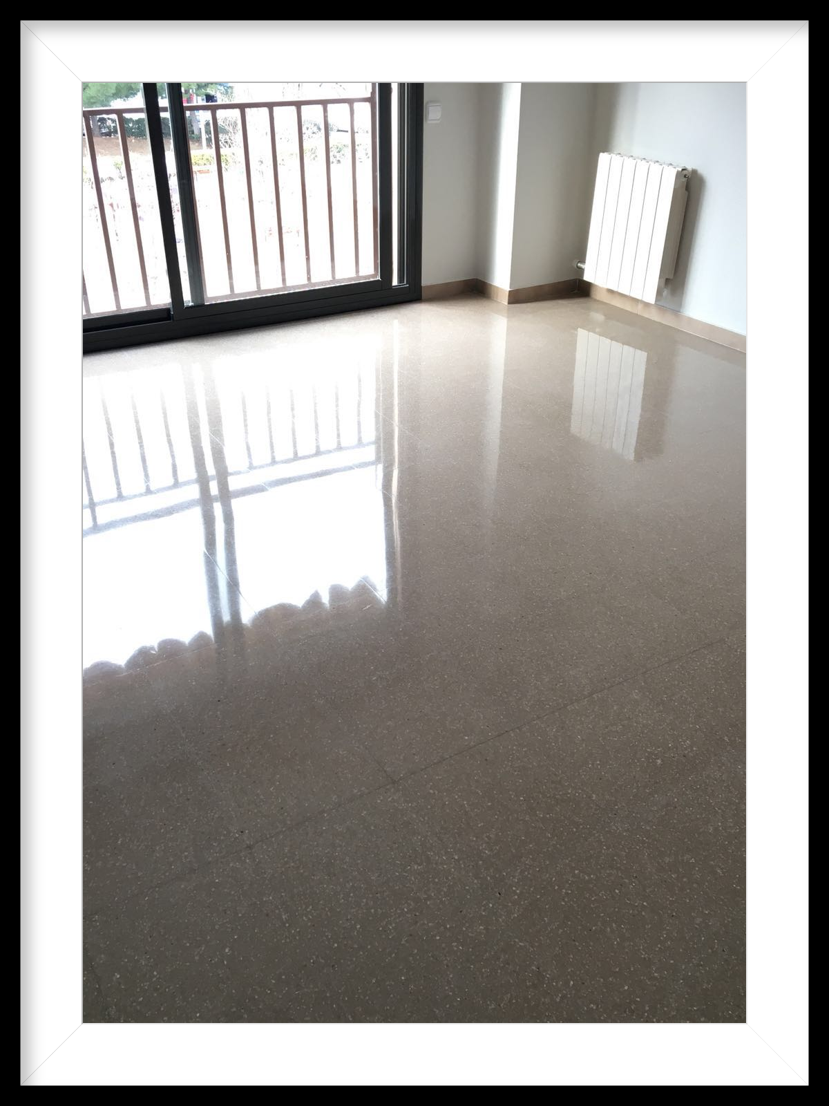Salón amplio con suelo abrillantado con reflejo de luz exterior.