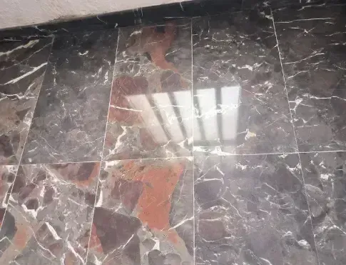 Primer plano de suelo de mármol pulido y cristalizado con reflejo nítido de luz en el techo.