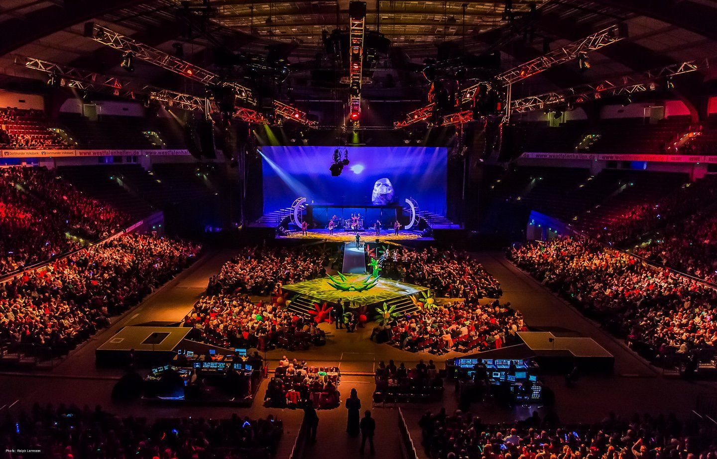 Fantastisch erleuchtet: Die große Veranstaltungshalle mit mehreren Bühnen und vollbesetzten Zuschauerrängen