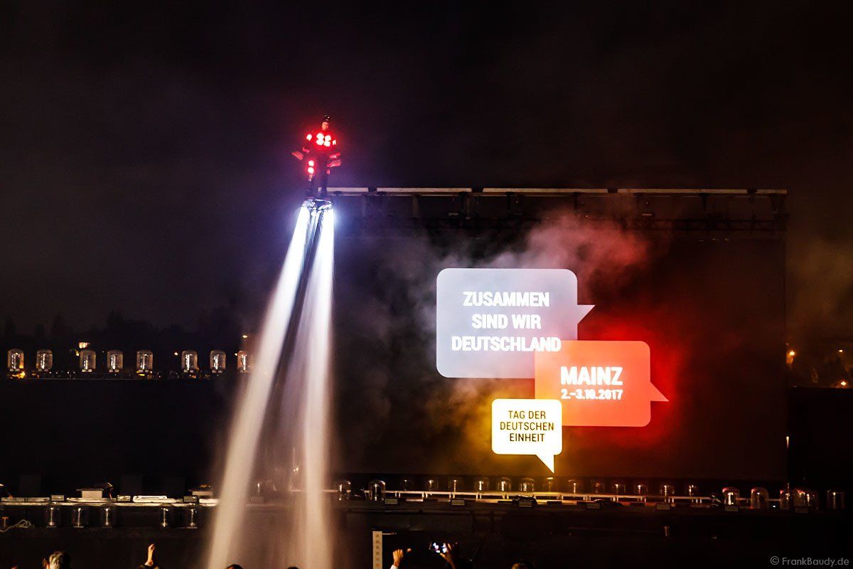 Jet Boarding Künstler in der Luft, dahinter Texte zum Tag der deutschen Einheit in Mainz