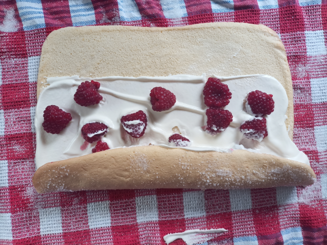 Teig mit Sahne und Beeren halb gerollt