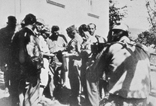 Le général Draja Mihaïlovic discutant avec le colonel McDowell entourés d'officiers tchetniks et américains devant l'objectif du cameraman militaire américain tournant un documentaire consacré au général Mihaïlovic en septembre 1944 à Pragnani en Serbie.