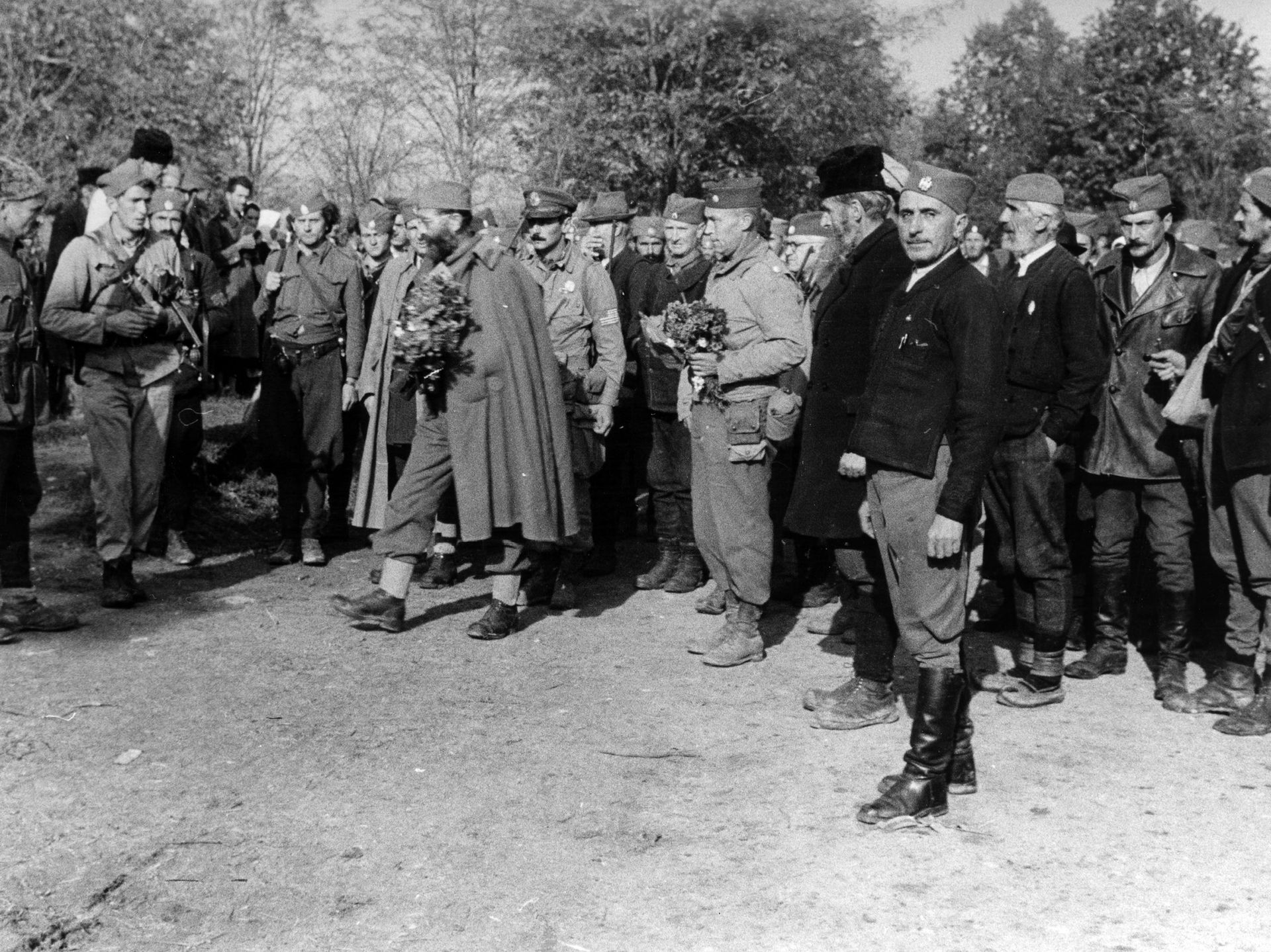 La population accueille le général
Draja Mihaïlovic et les officiers américains dans un village près de Doboï en Bosnie, en octobre 1944. Au milieu légèrement à droite, un bouquet de fleurs dans les mains le Col. McDowell
(Coll. particulière.)