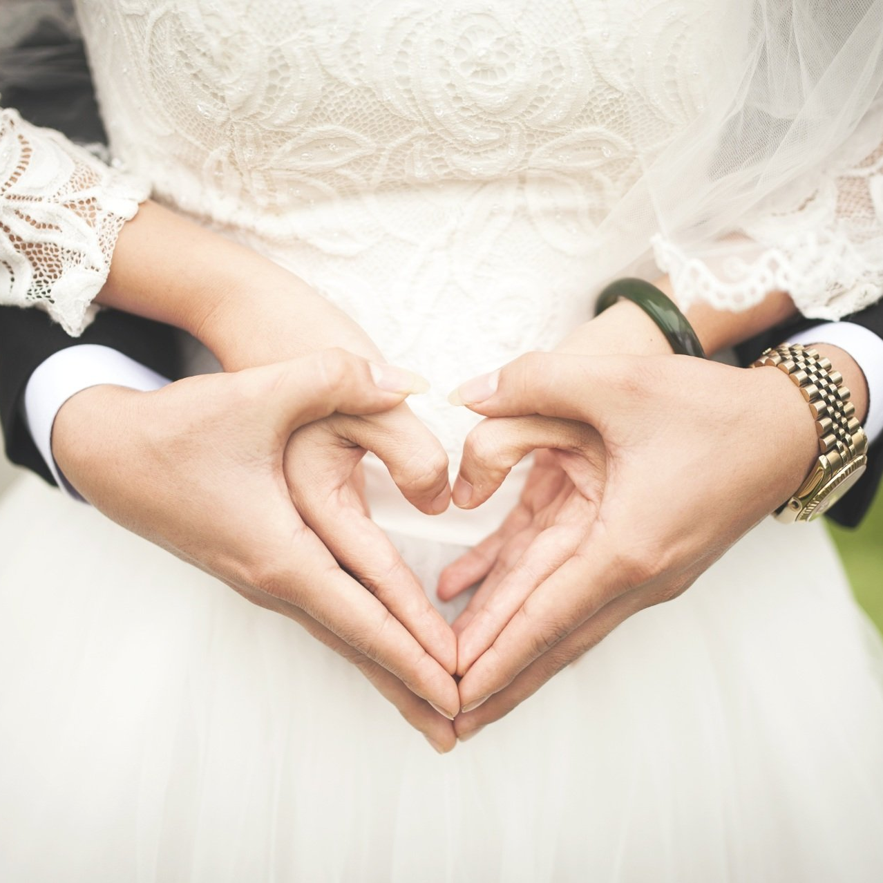 Hände des Brautpaares zeigen gemeinsam ein Herz, Hochzeit