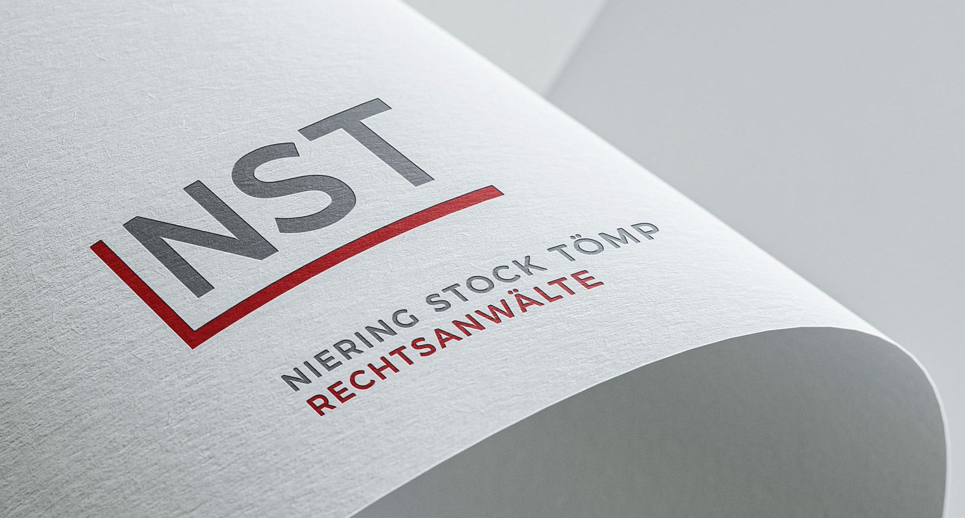 NST Logo NST Logo auf einem gewölbten, weißem Strukturpapier