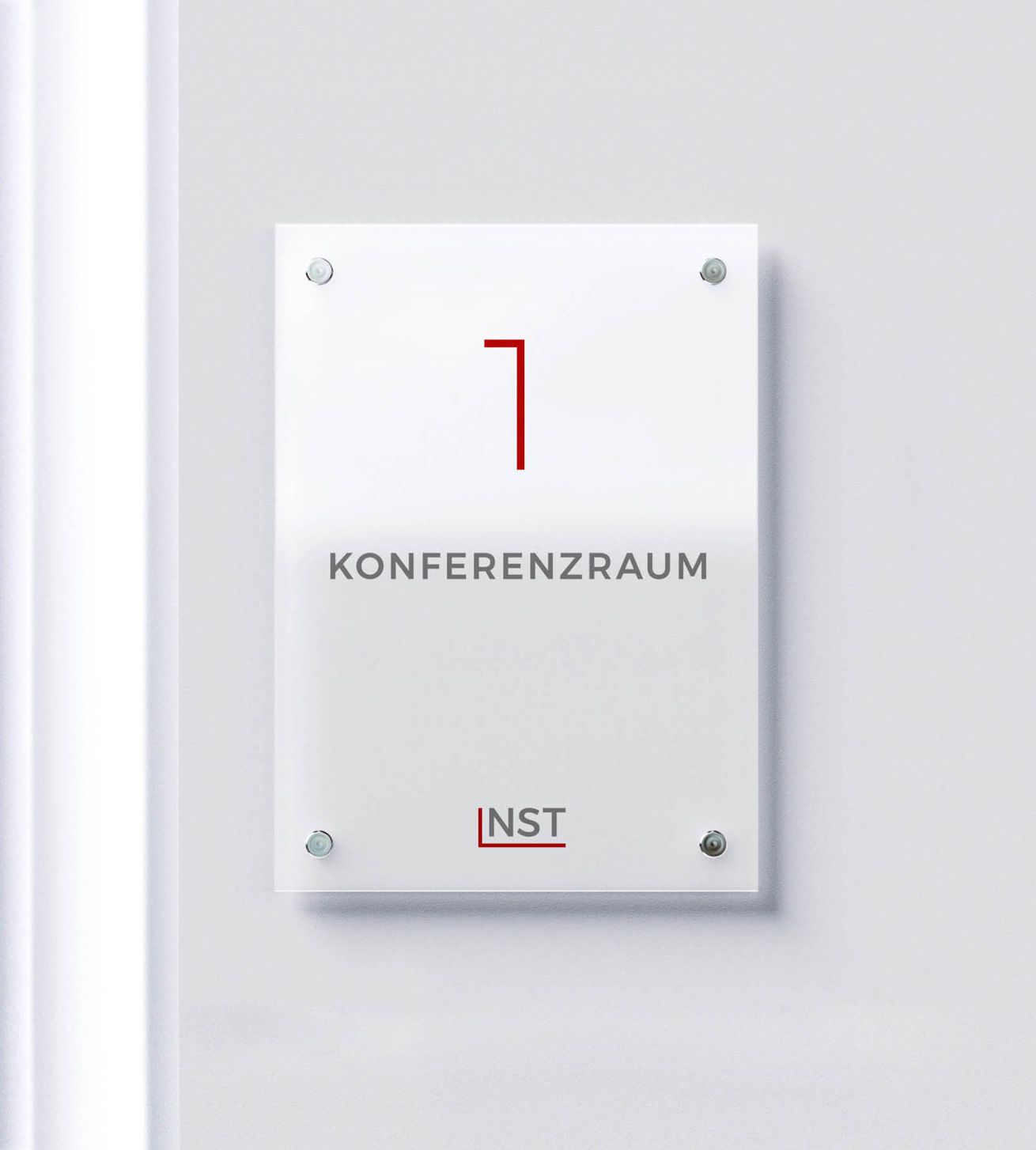 NST-Türschild Weißes Türschild auf weißer Wand. Auf dem Schild sieht man eine rote Eins mit der Unterzeile „Konferenzraum“, darunter das NST-Logo.