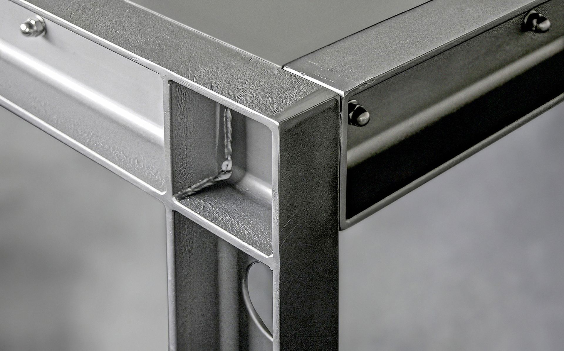 SF-Furniture-manufacture, Detailaufnahme eines gewinkelten Tischbeins und einem Teil der grauen Arbeitsplatte