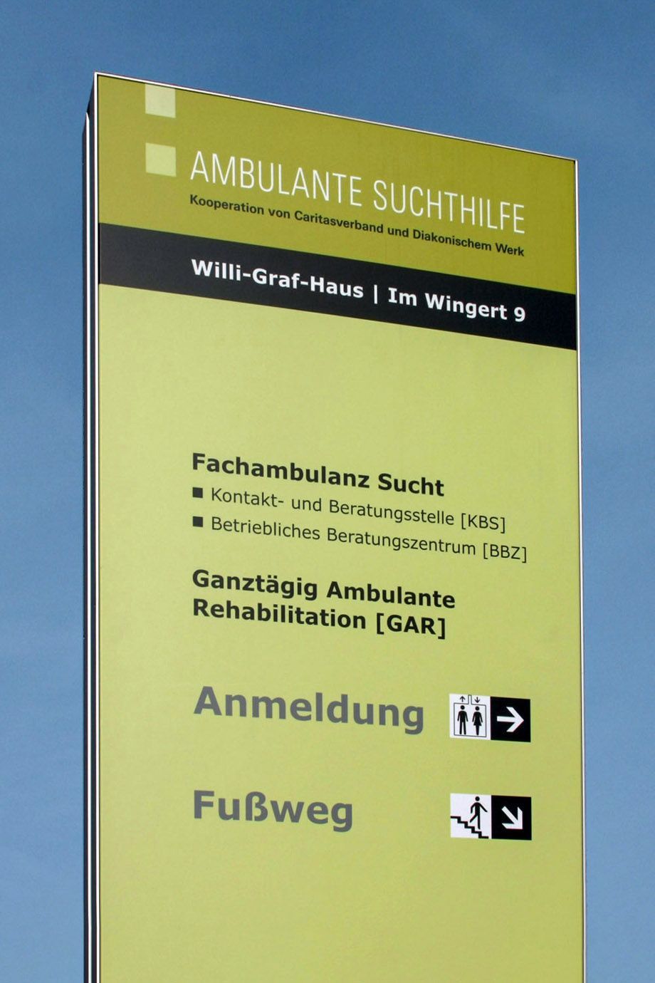 Infostele Stele der ambulanten Suchthilfe Bonn mit Hinweisbeschriftung und Logo auf grüngelber CD-Farbe.