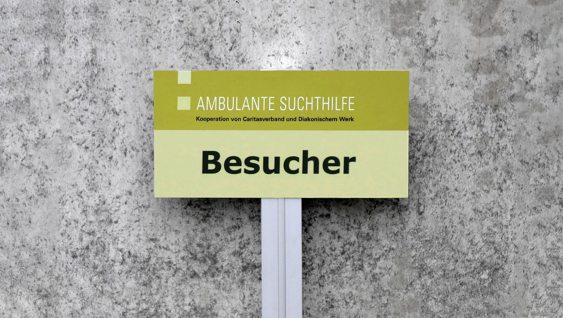 Parkplatzschild für Besucher Parkplatzschild für Besucher vor einer grauen Betonwand.