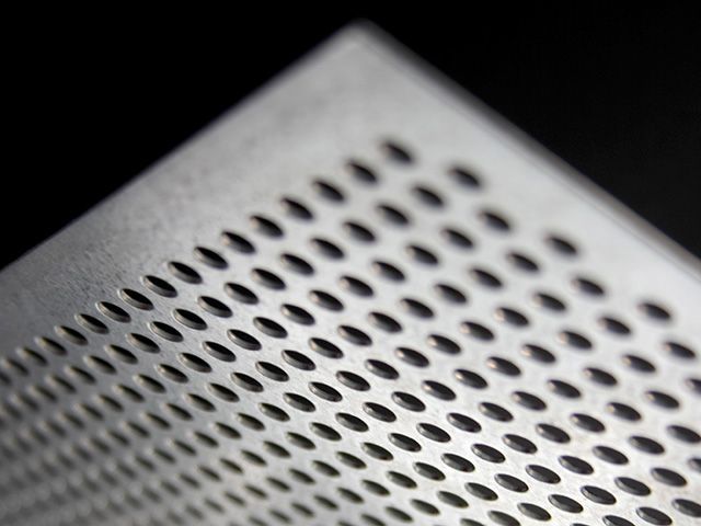 Lochblech Detailaufnahme eines gewinkelten Lochblechs, nach hinten unscharf, schwarzer Hintergrund.
