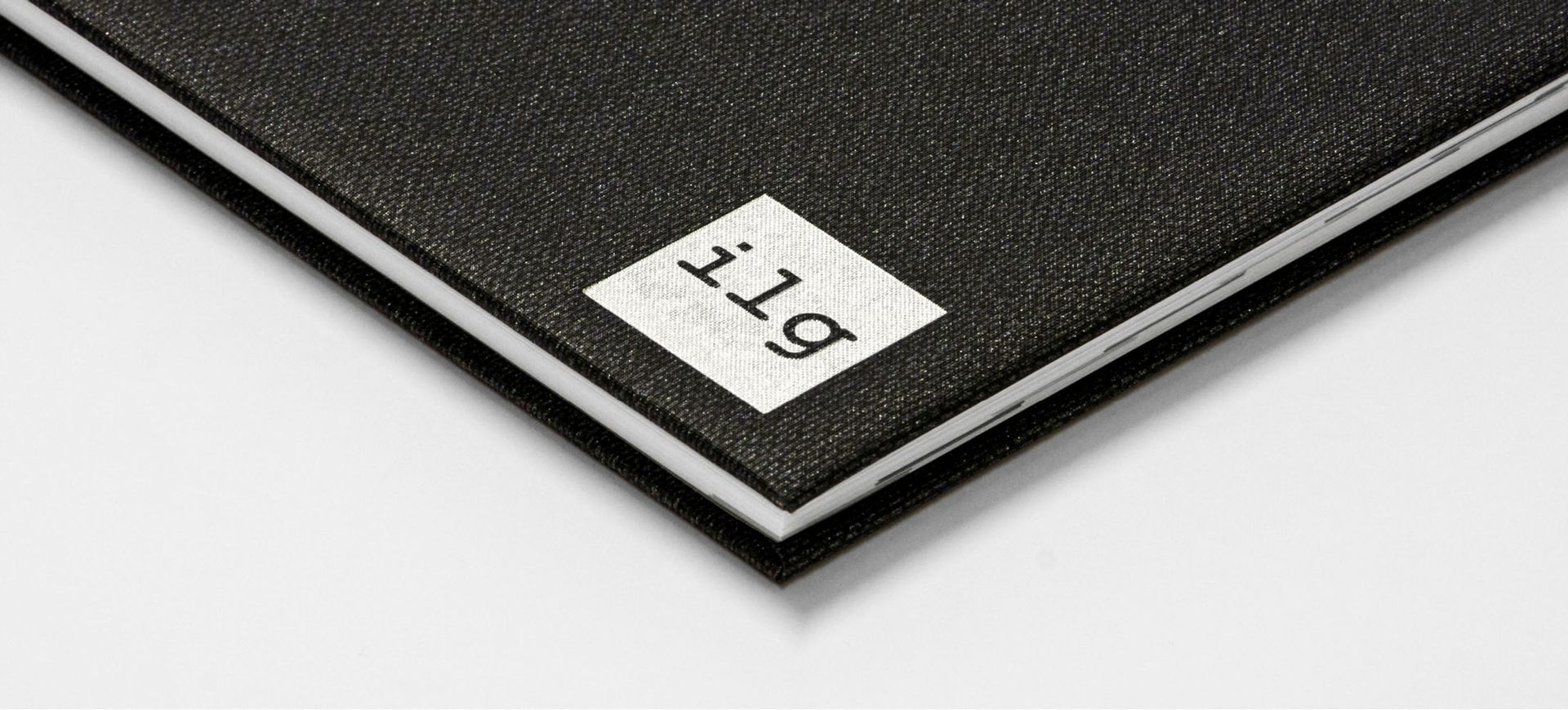Coverdetail Gewinkelte Detailansicht eines Buchcovers mit ilg Logo. Das Covermaterial ist aus schwarzem Stoff mit Struktur. Das Logo ist mit silberner Farbe aufgedruckt und am unteren rechten Rand platziert.