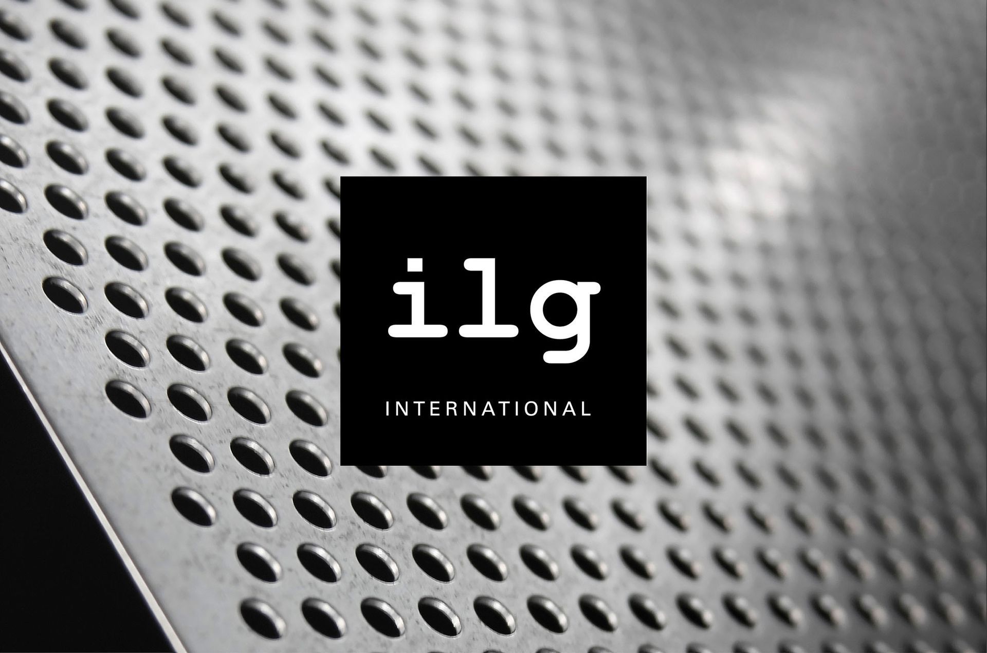 ilg Logo Logo, ilg International, weiße Schrift im schwarzen Quadrat vor einem Foto, das ein Lochblech zeigt, welches leicht nach links gewinkelt ist und nach hinten in die Unschärfe führt.