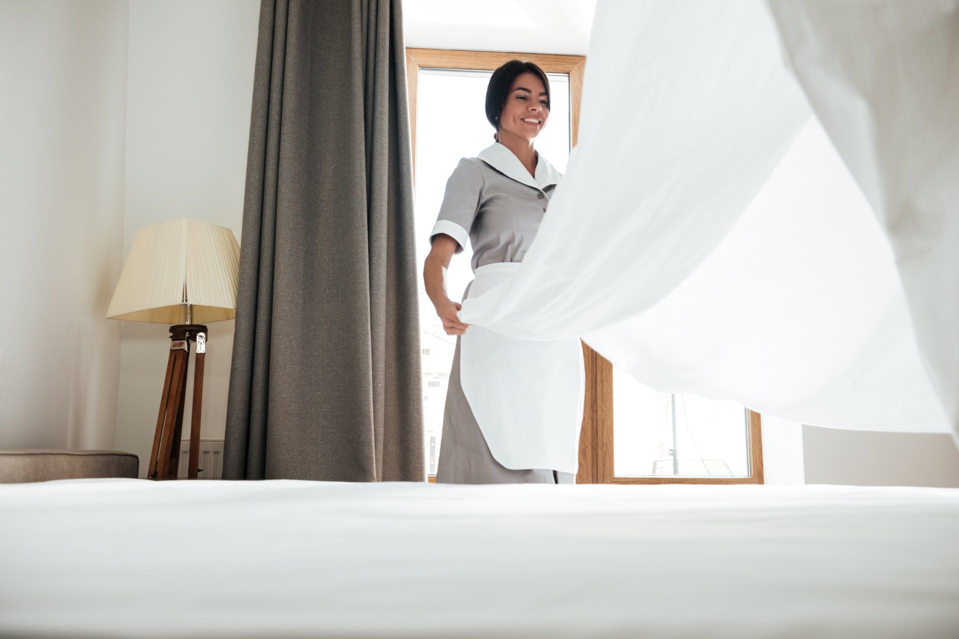 Chambermaid changing bed sheets
