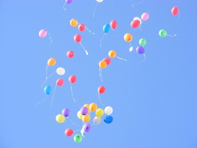 Fliegende Luftballons vor blauem Himmel.