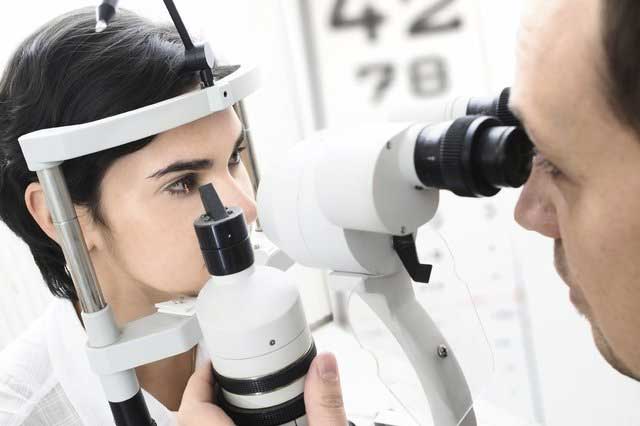 Optique of Lincoln Optician performing a eye test with a slitlamp microscope Optique of Lincoln Optician performing eye test
