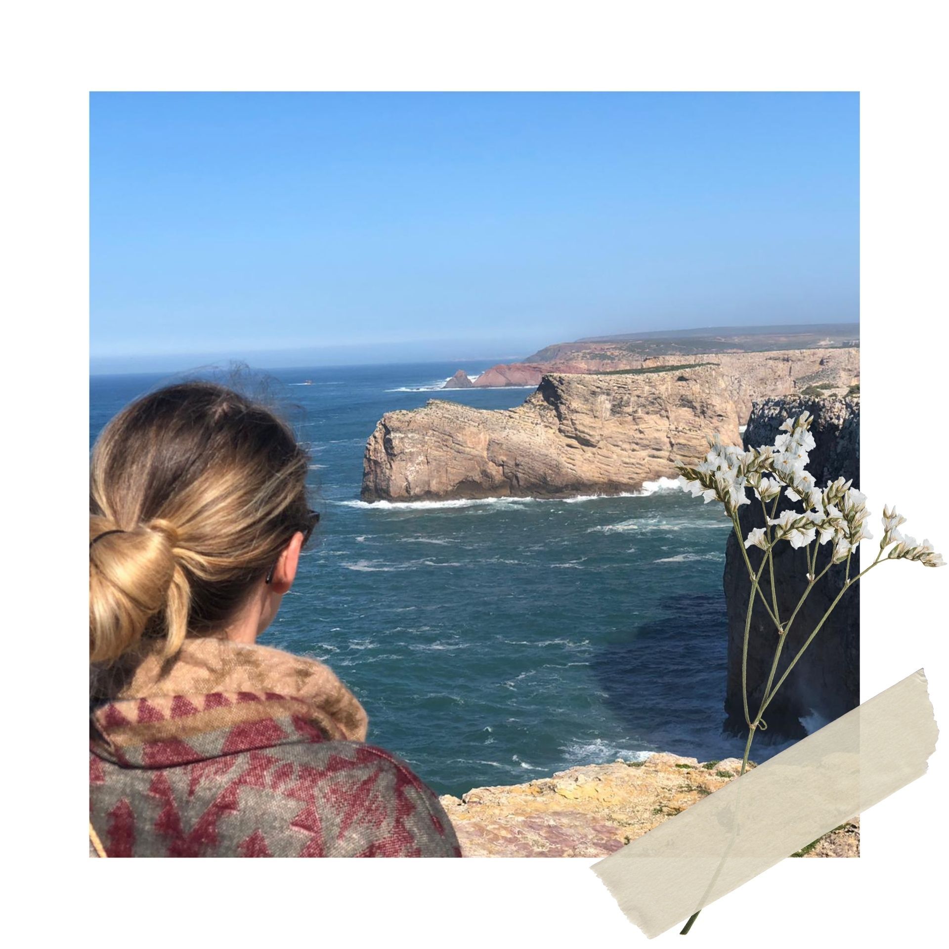 Eine Frau steht mit dem Rücken zur Kamera und blickt auf die Steilküste von Portugal.