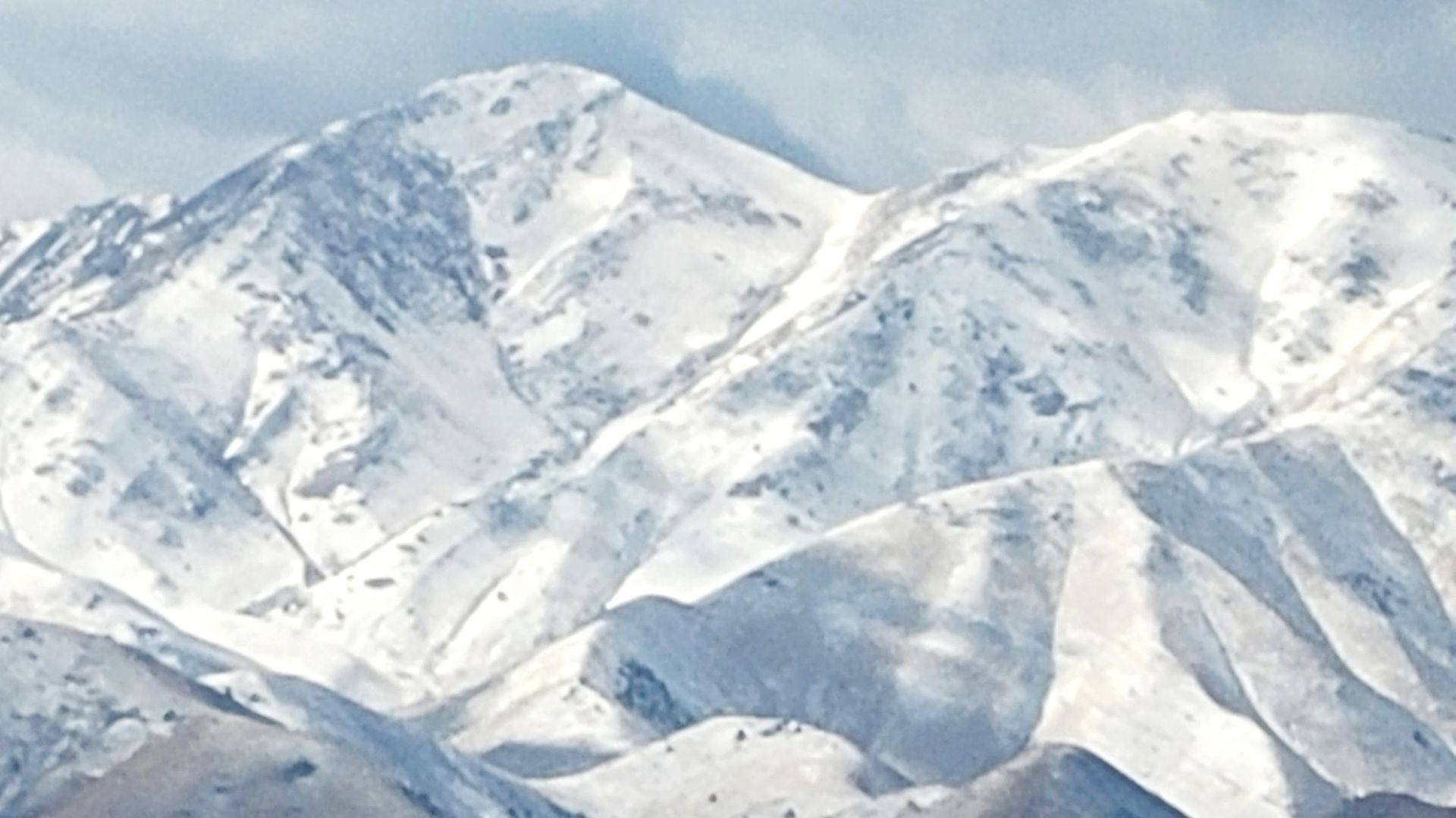 a picture of snowy mountaintops in Utah taken from the window of an airplane leaving Salt Lake City