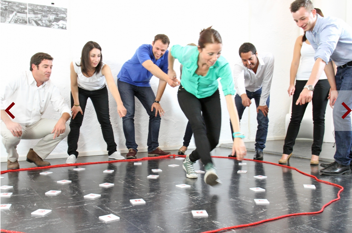 Seminarteilnehmer laufen über Karten mit einem roten Seil