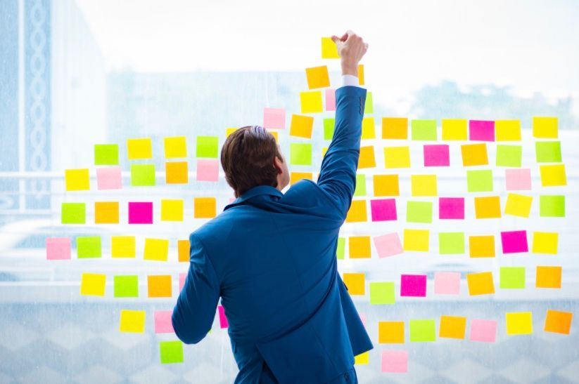 Mann klebt Post-its auf ein Fenster in Fisch-Form