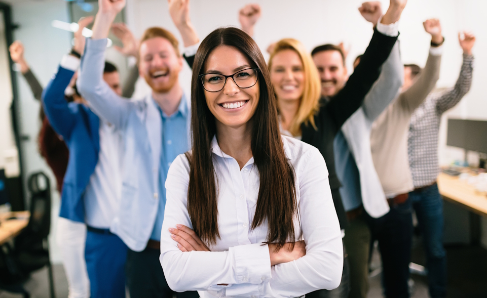 Eine Gruppe von Mitarbeitern jubelt einer Frau zu