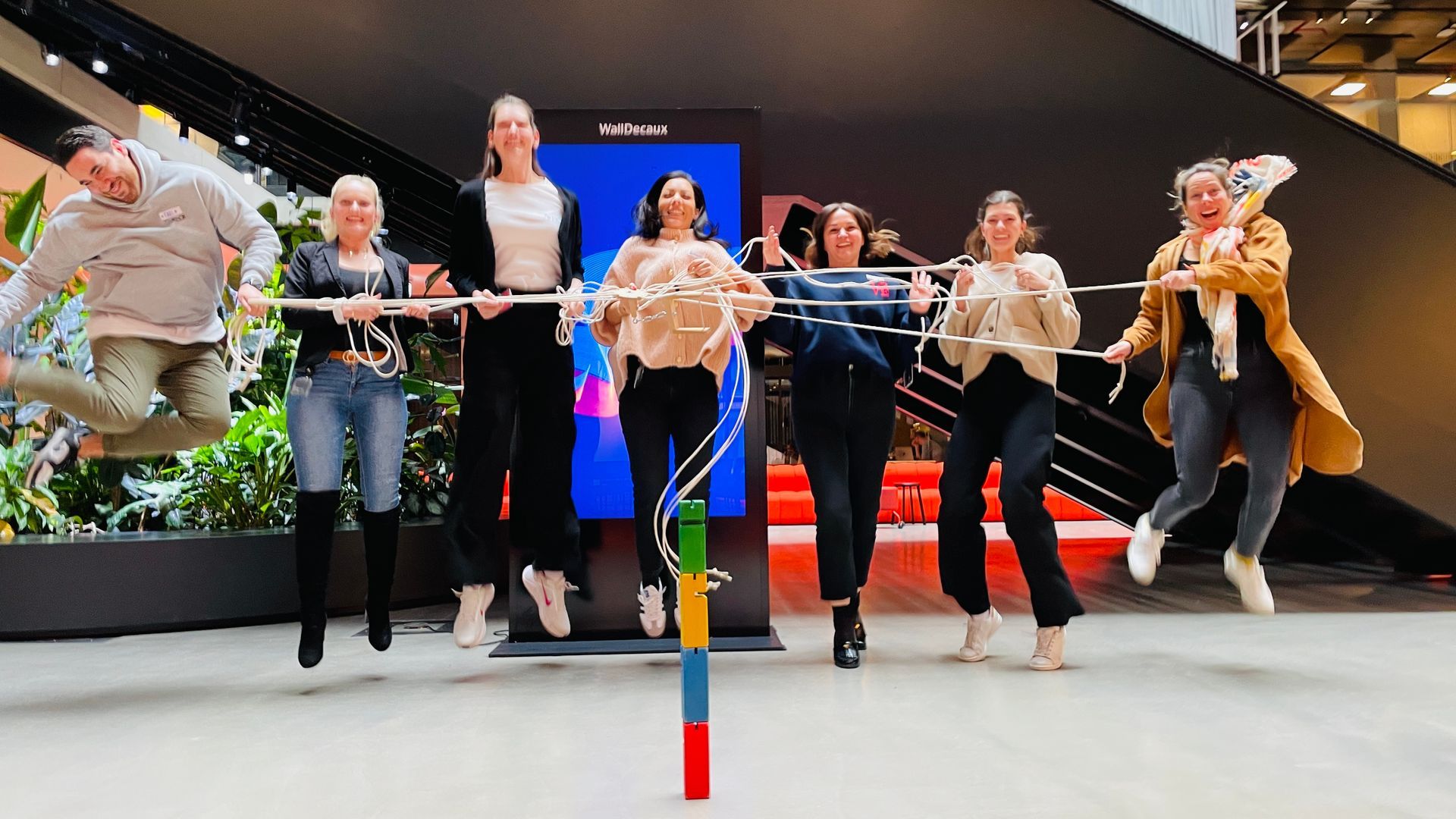 Seminarteilnehmer halten ein Seil und springen in die Luft