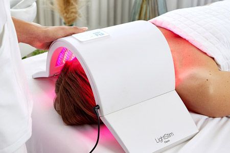 Frau liegt mit dem Gesicht unter der LED Lampe Elipsa von Lightstim.