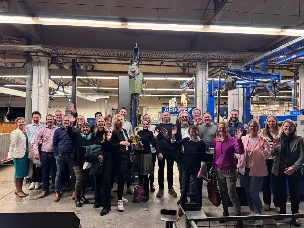 Eine Gruppe von Menschen in einer industriellen Umgebung mit Maschinen und Anlagen um sie herum.