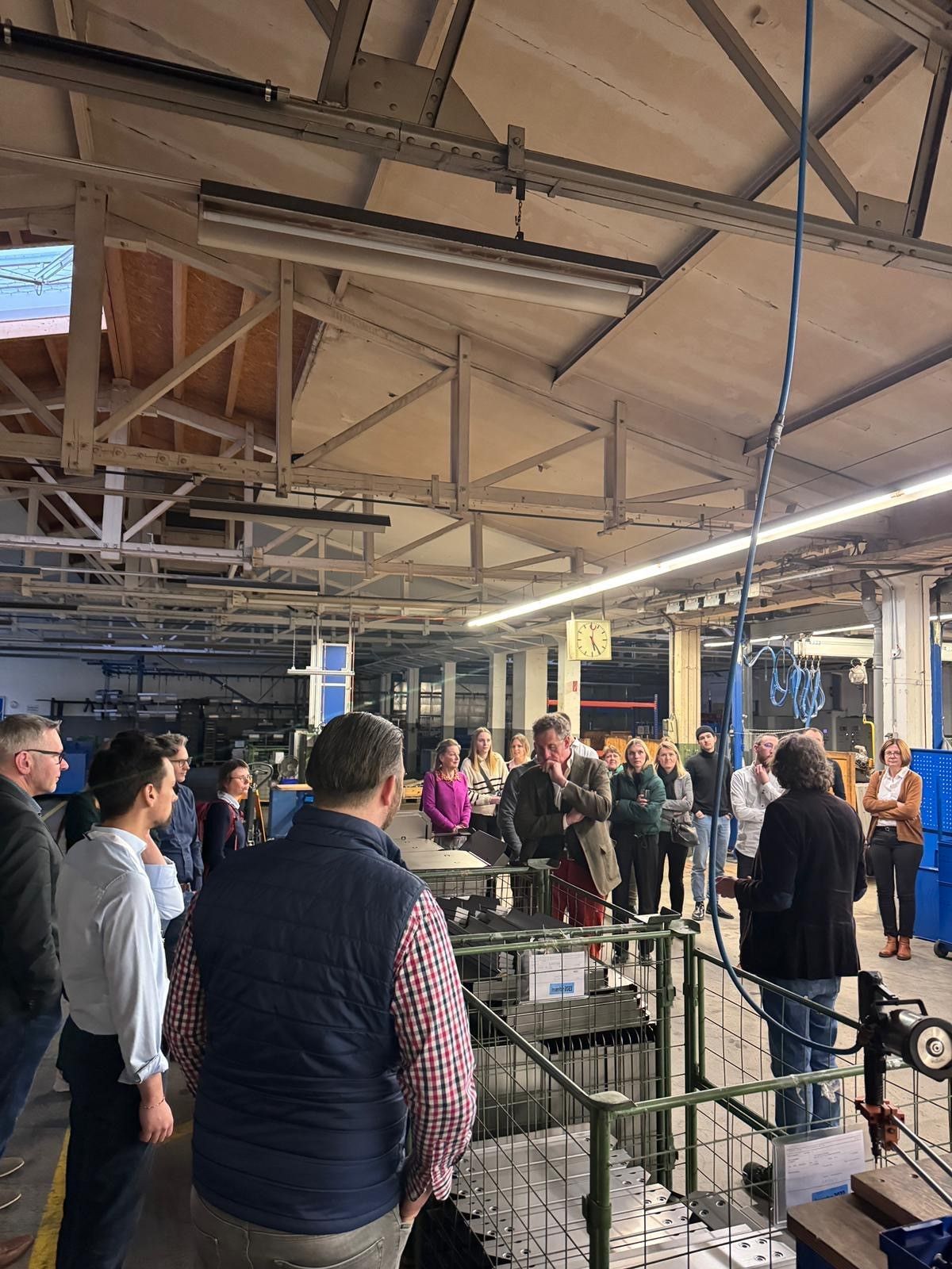 Eine Gruppe von Menschen verschiedener Geschlechter steht in der Fabrik von GEDORE und hört aufmerksam einer Person zu.