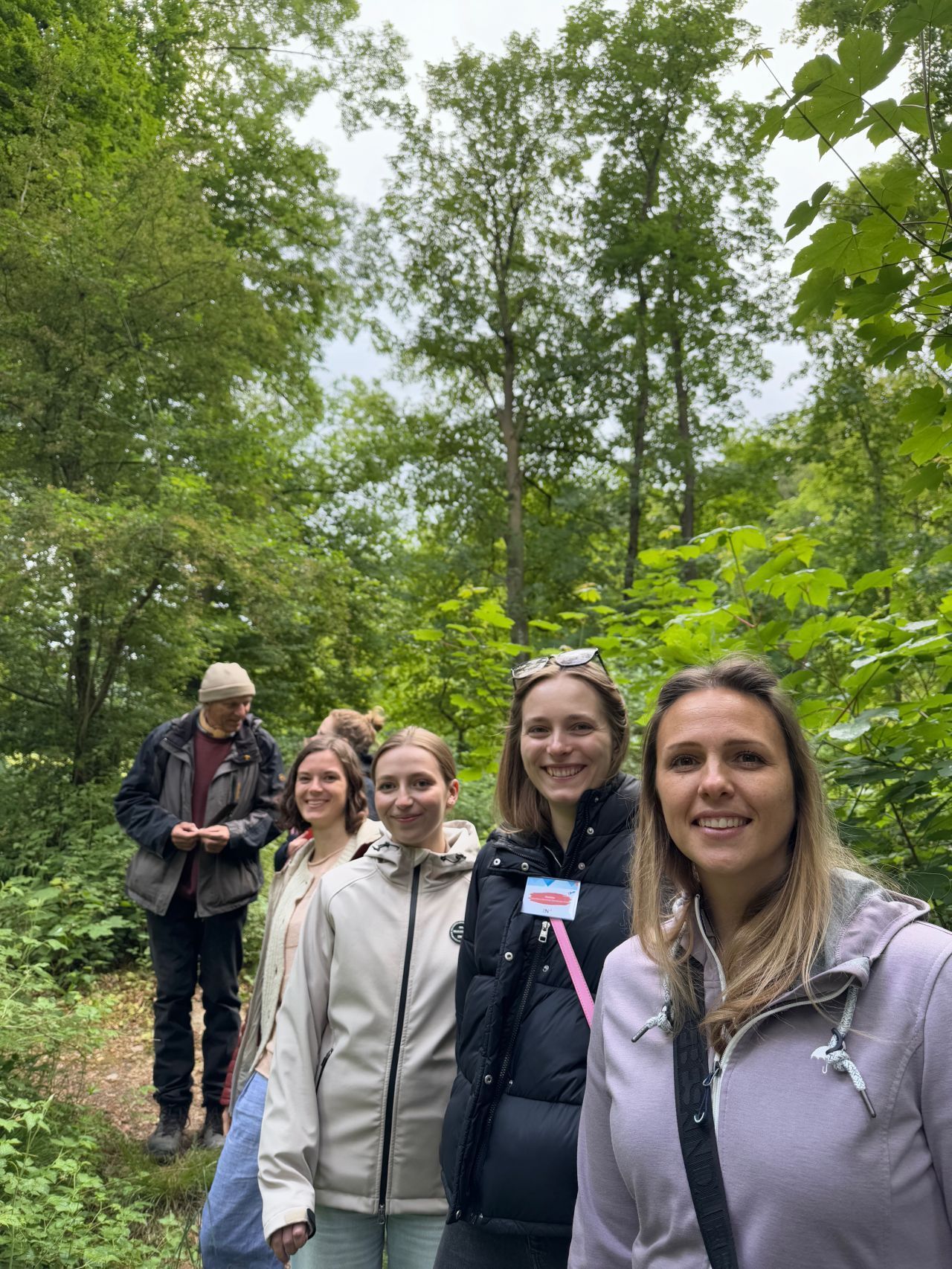 Mehrere Personen des Netzwerkes im Wald. Drei Frauen schauen in die Kamera und lächeln