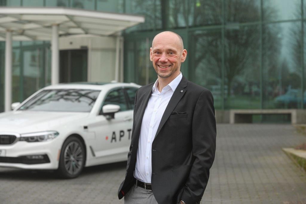 Matthias Laumann vor einem Auto mit Aptiv Logo