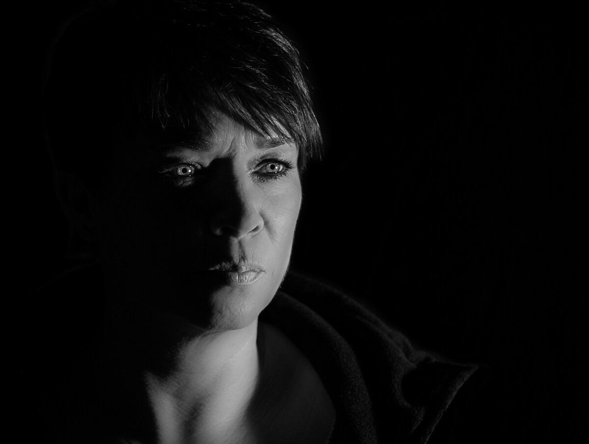 Ein Portait einer Frau in schwarz-weiß. Die rechte Gesichtshälfte liegt im Schatten.