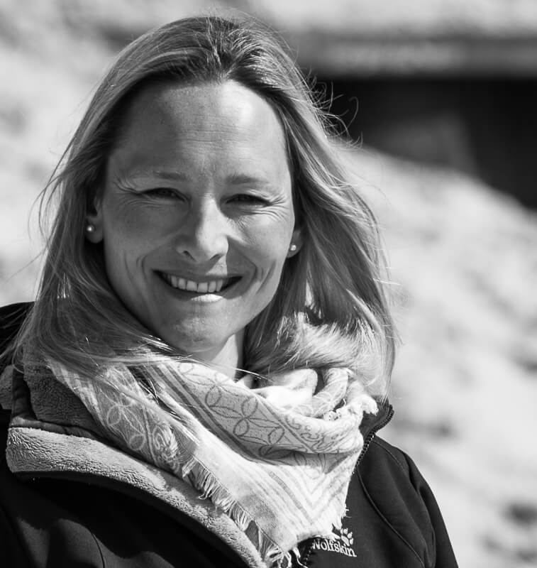 Ein Protrait einer lächelden Frau in schwarz-weiß am Strand..