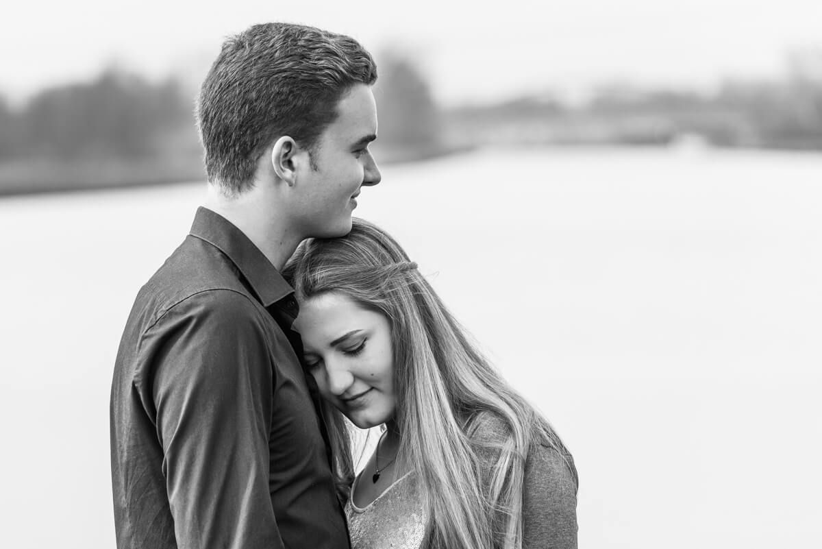 Portait von einem jungen Paar in schwarz-weiß. Sie lehnt ihren Kopf an seine Brust.