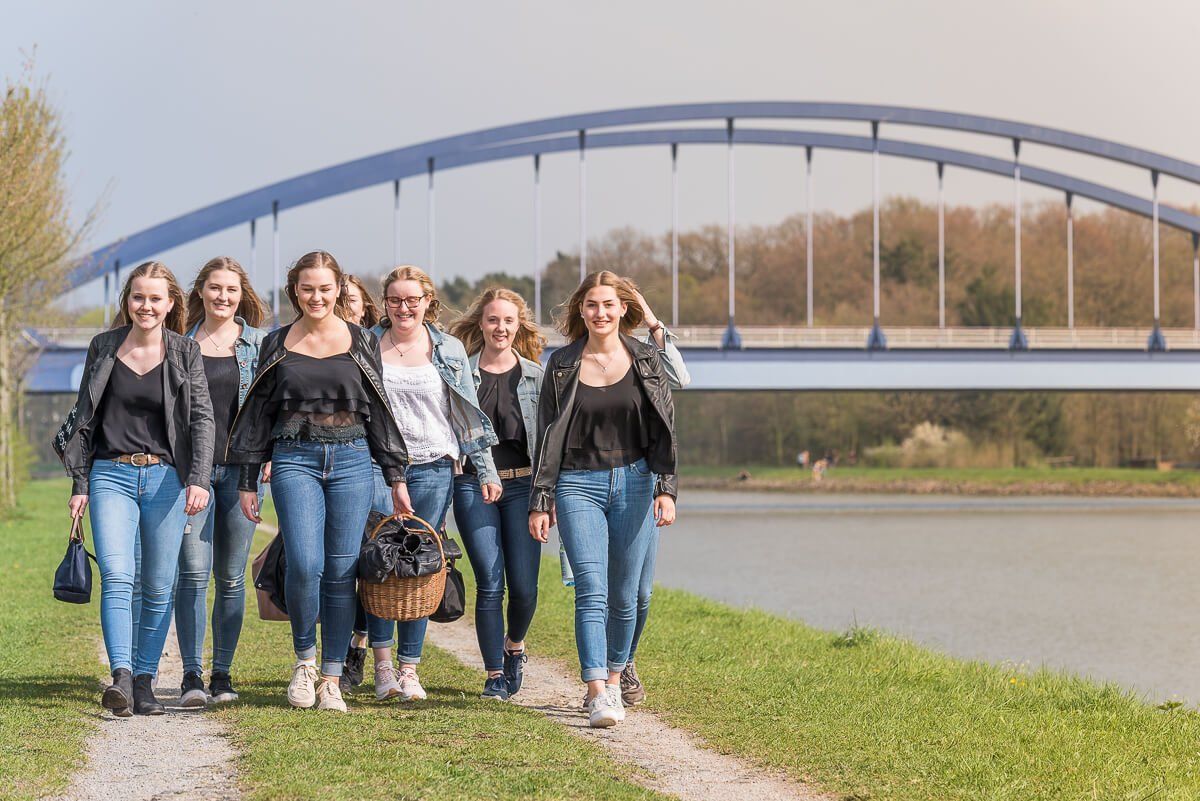 Neun junge Frauen am Dortmund-Ems-Kanal in Münster, die als Gruppe zusammen gehen.