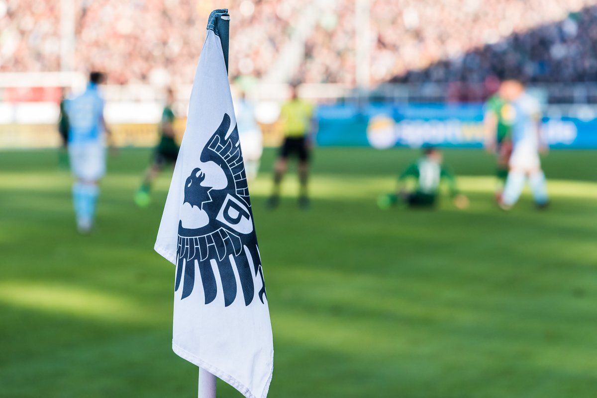 Eine Agility-Sportlerin lässt Ihren Hund während einer Vorführung über eine Hürde springen.