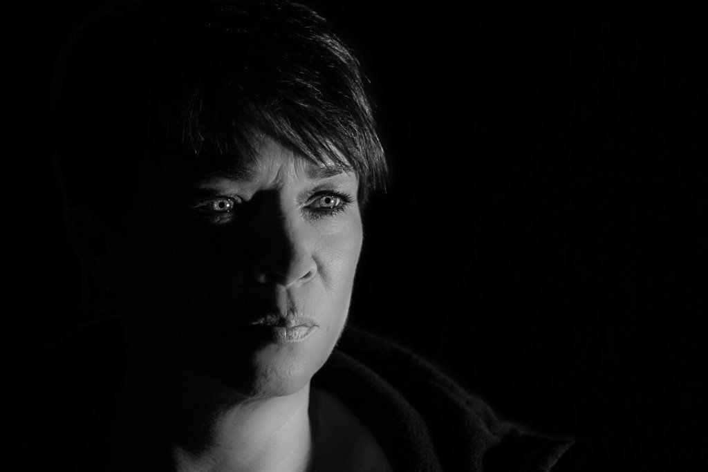 Portrait einer Frau in schwarz-weiß mit Schatten auf der rechten Gesichtshälfte.