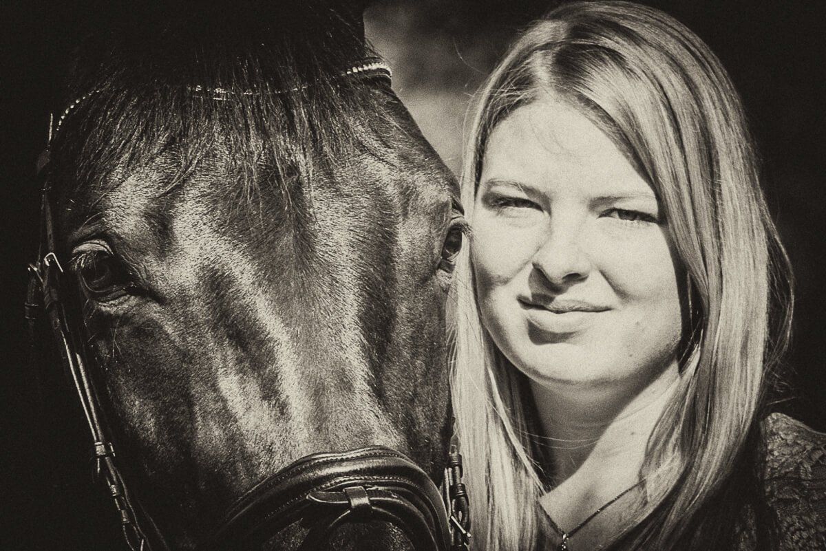 Ein Portrait einer jungen blonden Frau mit ihrem Pferd in sepia.